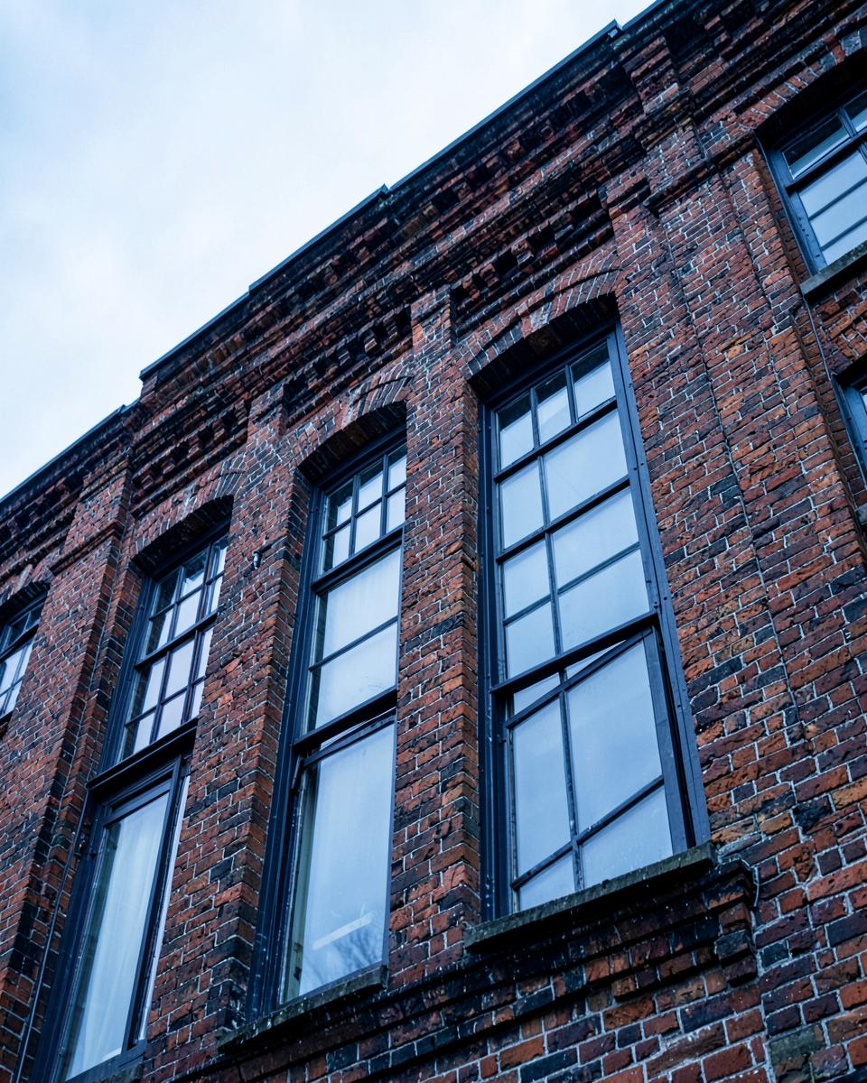 Victorian brick industrial facade with steel-framed windows, seen from below