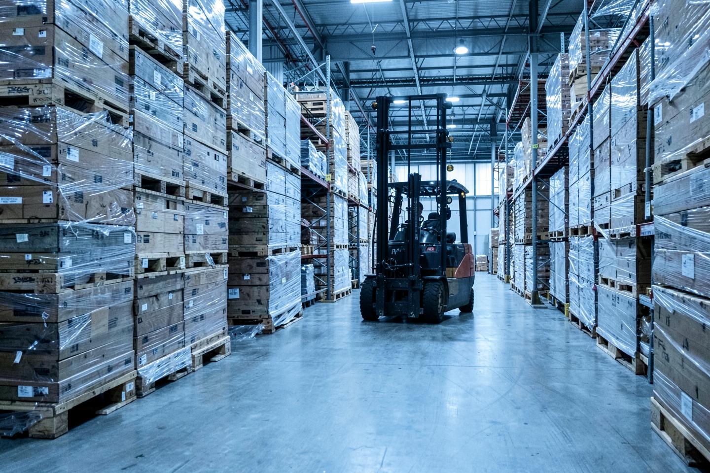 Stacked pallets and a forklift in a distribution warehouse aisle