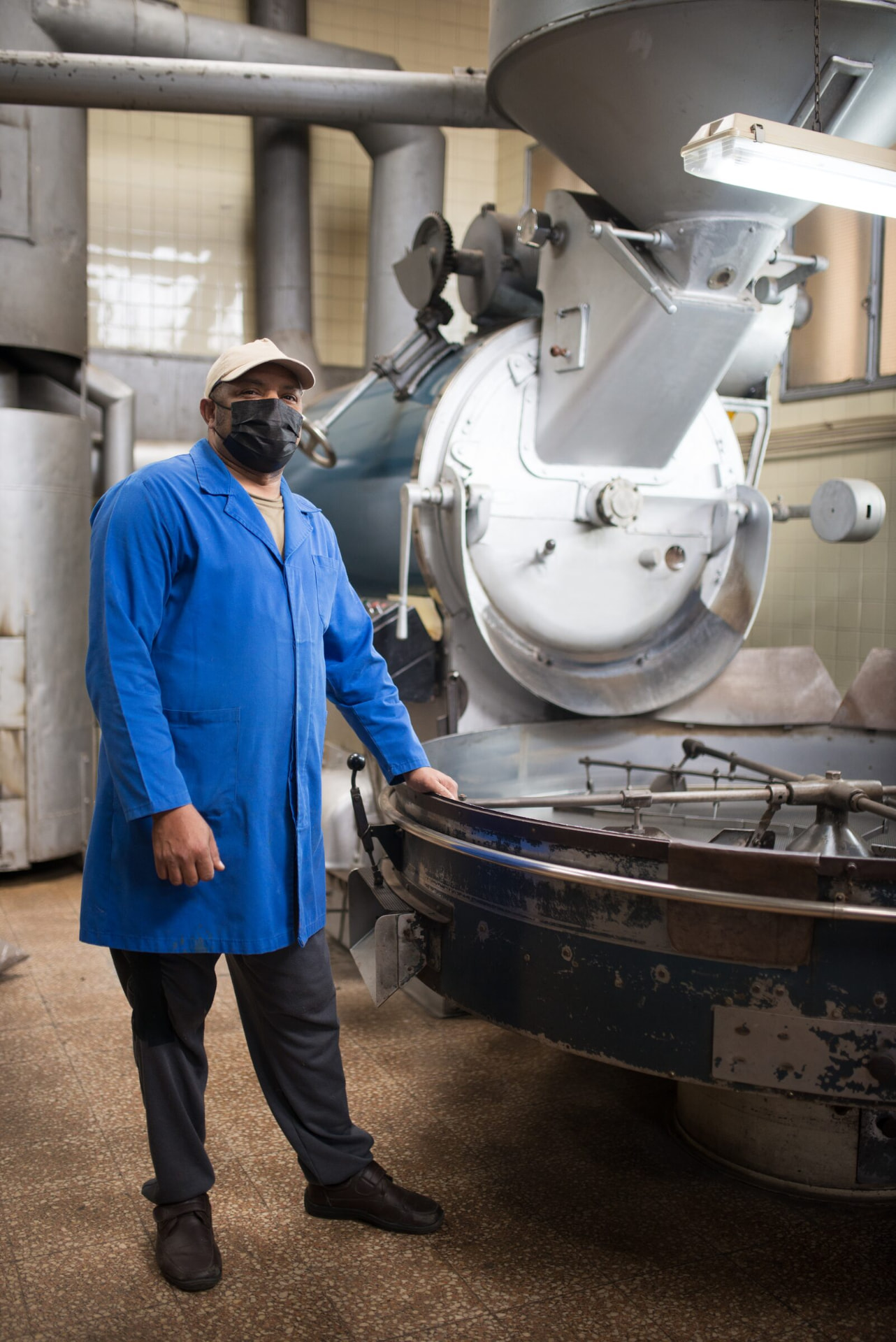 Operator beside a coffee roasting drum in a production workshop